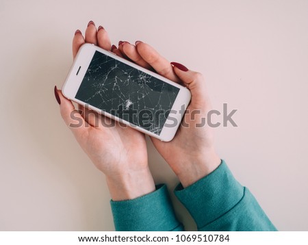 Broken glass screen smartphone in hand, white background.