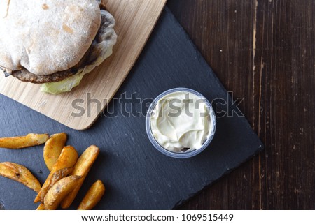 BBQ burger with grilled meat and potatoes on dark surfaceClose-up