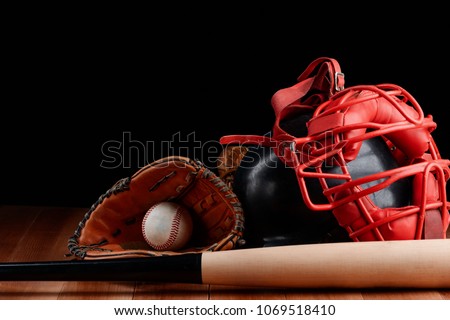 Ball, glove, helmet and bat. Baseball equipment items on a wooden table on black background.