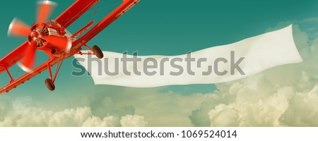 Vintage red airplane flying in the sky with a white blank banner