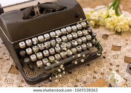 Spring or summer freelance and writing concept. Retro typewriter with gypsophila flower in its keys on lace table cover.