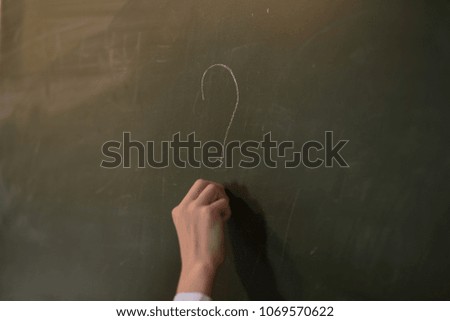men writing question marks on blackboard