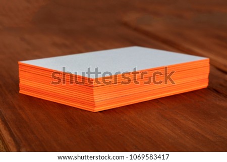 A stack of blank layered business cards with painted edges, on a dark background, with a shallow depth of field. Selective focus photo, place for text.