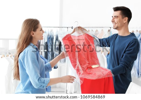 Young woman receiving her dress at dry-cleaner's Royalty-Free Stock Photo #1069584869