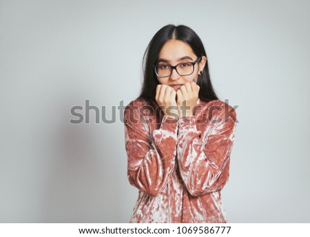 beautiful asian woman worried, wearing glasses and pink sweater, studio photo on background