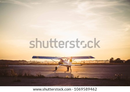 Plane on the runway in the rays of the sun. Airport sunset. Royalty-Free Stock Photo #1069589462