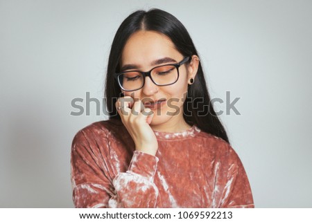 beautiful asian woman is shy, wears glasses and a pink sweater, studio photo on a background