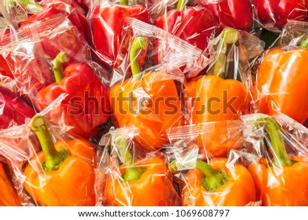 Bunch of plastic wrapped orange and red bell peppers Royalty-Free Stock Photo #1069608797