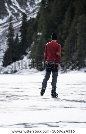 Ice skating on a mountain lake boy with red jersey