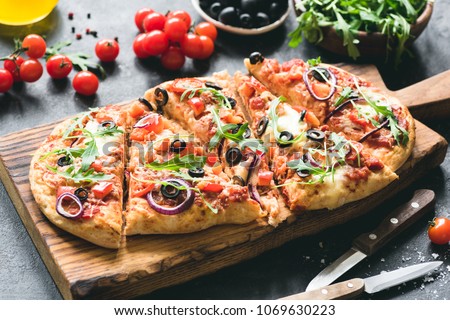 Homemade flatbread pizza garnished with fresh arugula. Selective focus Royalty-Free Stock Photo #1069630223