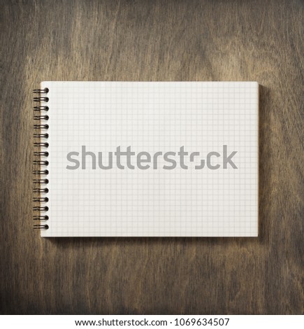 checked notebook at wooden background