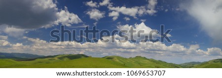 Panoramic view of green hills and blue sky with clouds