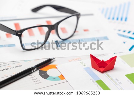 Boats made of paper graph on notebook with glasses and pen.Business Analysis concept.