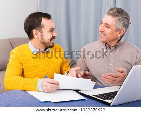Young man and sales manager discuss terms of contract of purchase at home