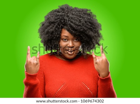 Beautiful african woman making rock symbol with hands, shouting and celebrating