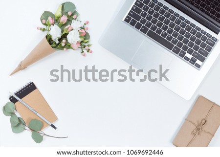 Top view of white office desk table with laptop, notebook, flower composition. Copy space, flat lay.