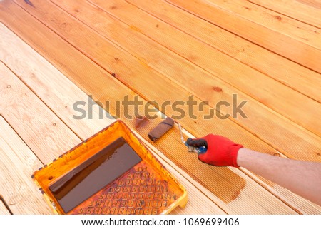 Painting a terrace board impregnation water proofing. Carpenter painting wood. Royalty-Free Stock Photo #1069699406