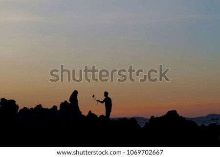 silhouette of asian man take a selfie on the beach with sunset