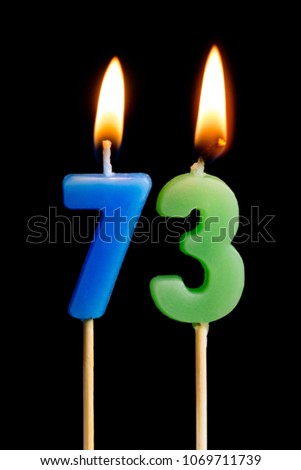 Burning candles in the form of 73 seventy three (numbers, dates) for cake isolated on black background. The concept of celebrating a birthday, anniversary, important date, holiday, table setting