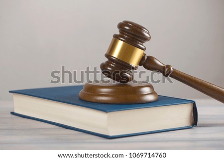 Wooden mallet used by a judge or at an auction next to a book. Concept