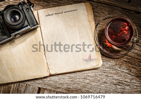 about travel memories. Old notepad with a blank page and an old camera on a wooden background. Concept: travel. Copy space