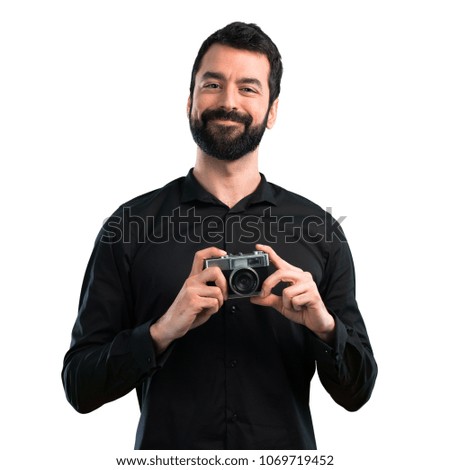Handsome man with beard holding a camera on white background