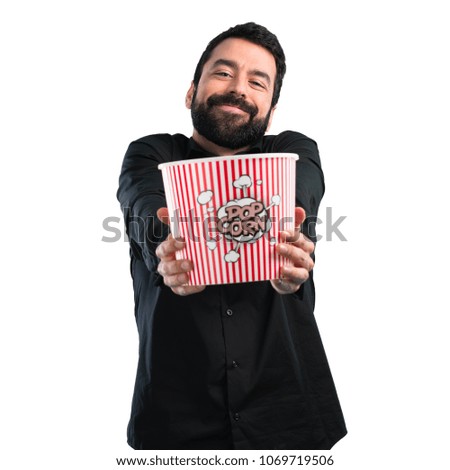 Handsome man with beard eating popcorns on white background
