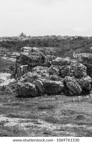 The Megalithic Temples of Malta are the oldest free-standing structures on Earth on the background of city of Victoria. Black and white picture 