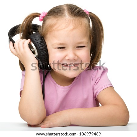Cute little girl enjoying music using headphones, isolated over white