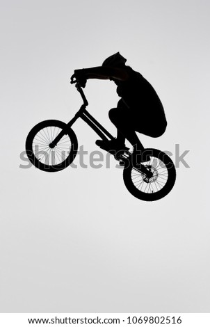 silhouette of trial cyclist jumping on bicycle on white