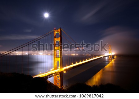 The Golden Gate Bridge under the moonlight, with fog engulfing San Francisco.