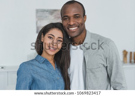 smiling african american girlfriend and boyfriend looking at camera at home