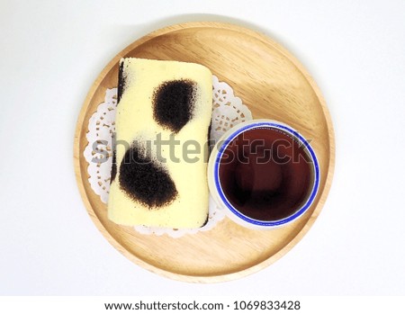 Black tea in white cup and white cream roll cake on wooden board.white background.