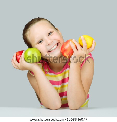 Cheerful little girl with fruit posing in studio