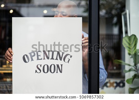 Man putting on store opening soon sign Royalty-Free Stock Photo #1069857302