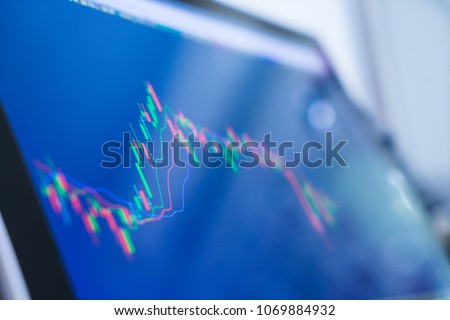Computer screen with selective focus of technical price graph and indicator, red and green candlestick chart, market volatility, up and down trend. Stock trading, crypto currency background. Royalty-Free Stock Photo #1069884932