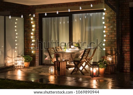 Summer evenig terrace with candles, wine and lights Royalty-Free Stock Photo #1069890944