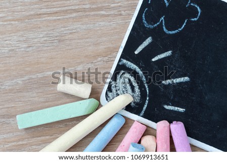 Multicolored chalks for drawing near a black board with a pattern.
