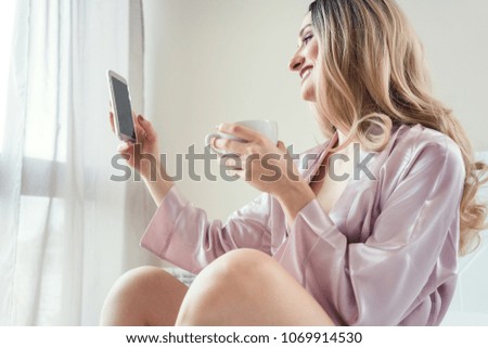 Woman doing a morning selfie with phone in her bedroom 