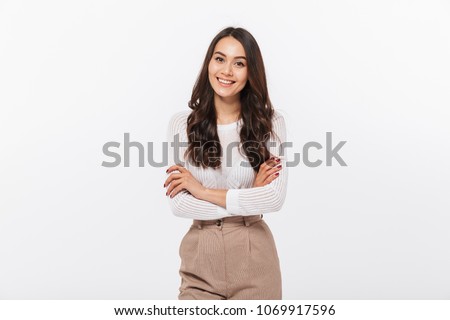 Portrait of a smiling asian businesswoman standing with arms folded and looking at camera isolated over white background