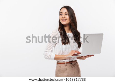 Portrait of a happy asian businesswoman holding laptop computer iand looking away solated over white background