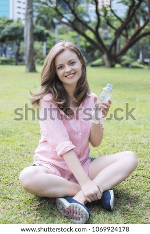 Young caucasian woman holding plastic bottle with water in her hand. Outdoor picture