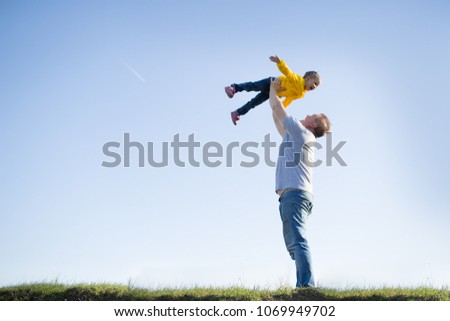 dad and daughter are standing on the grass against the sky