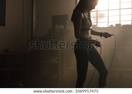 Fitness woman with jumping rope in gym. Female exercising with skipping rope at health club. Royalty-Free Stock Photo #1069957475