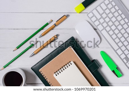 Wooden White office desk table with cup of coffee, Notebook, Pen, Marker, Computer Keyboard Mouse on it. Top view with copy space