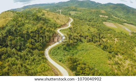 A long and winding road passing through green hills. Busuanga island. Coron. Aerial view. Philippines.