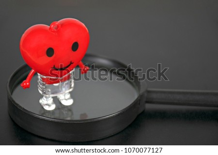 Heart red toy on Magnifier and black background.Concept screening and care for the heart.