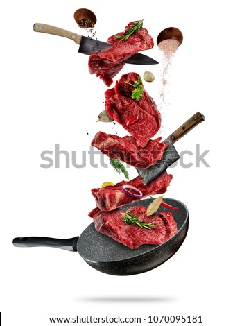 Flying pieces of beef steaks from pan, isolated on white background. Concept of flying food, very high resolution image