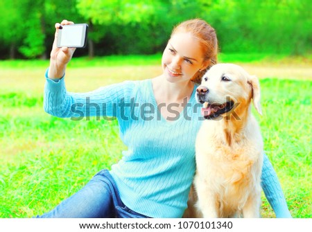 Golden Retriever dog is taking picture selfie portrait on a smartphone on a summer day