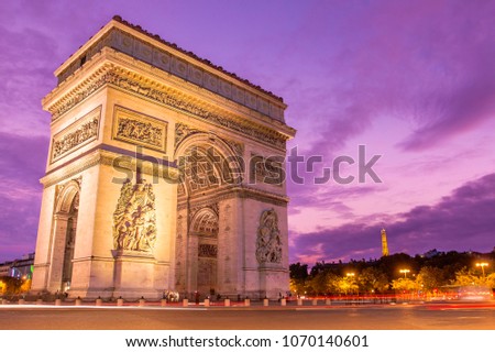 Amazing ornamental monument of Arc de Triomphe illuminated in twilight with violet sky on background in Paris, France